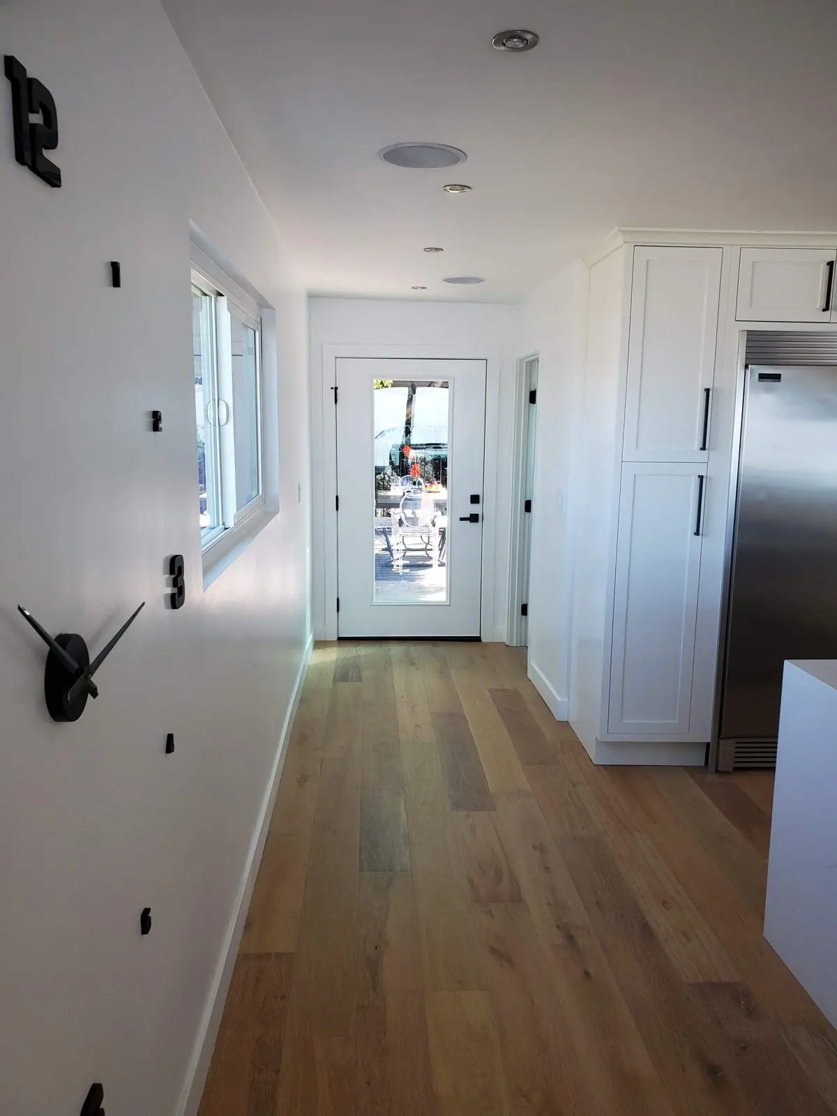 Hallway with wide oak plank flooring leading to a glass-panel door