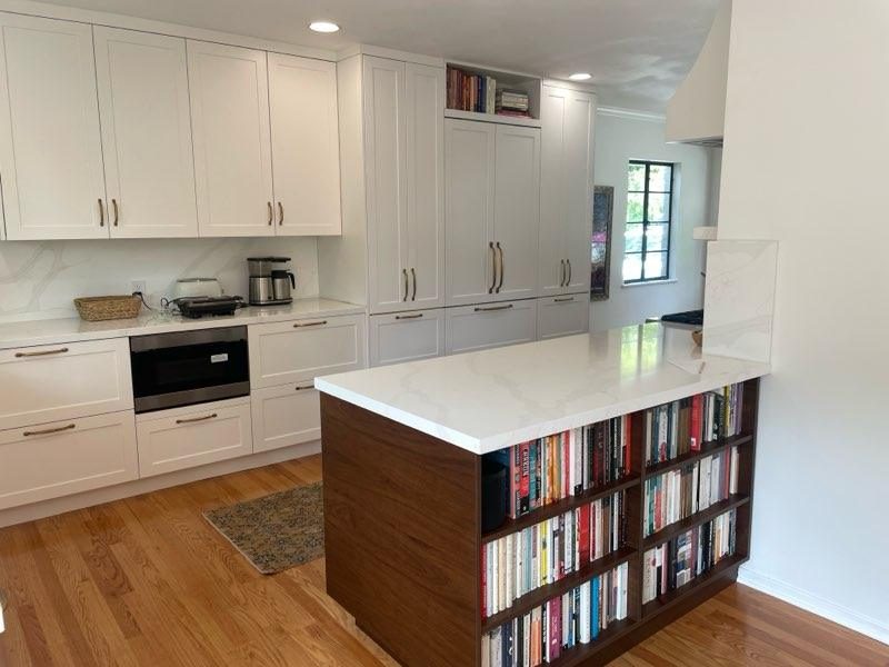 White kitchen with a quartz peninsula and built-in bookshelf